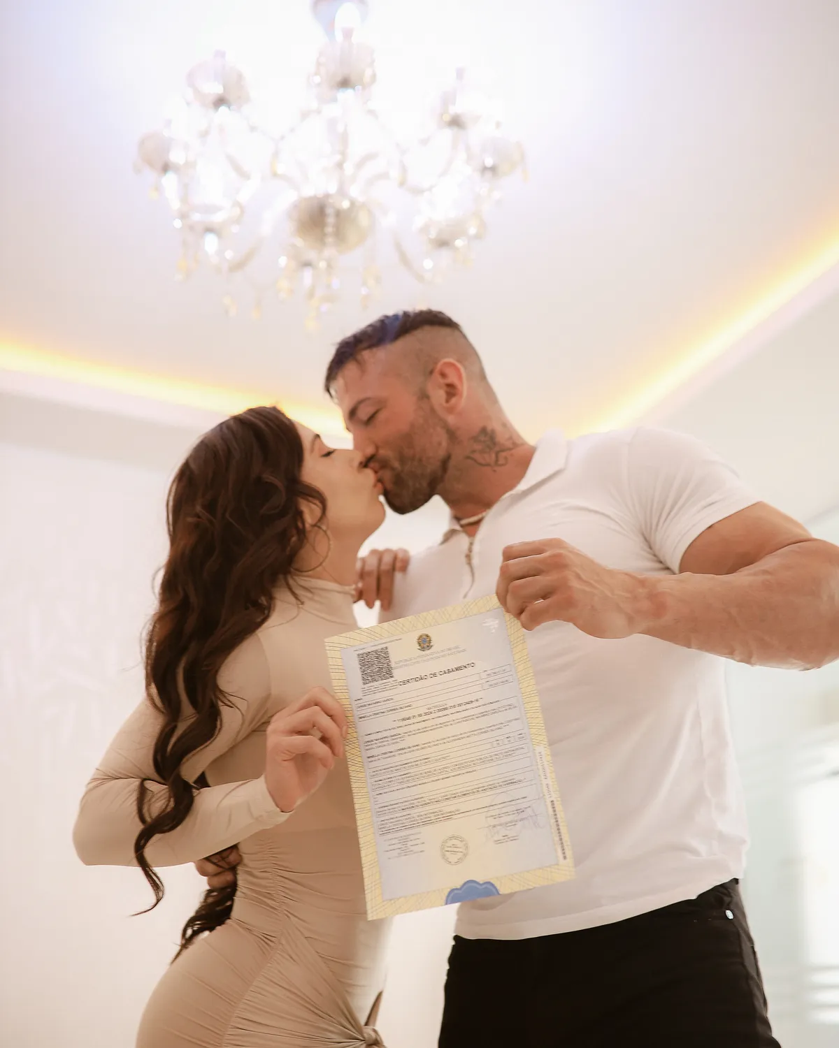 Maximo Garcia com uma mulher num ambiente claro, segurando um documento assinado